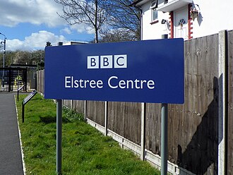 Road sign to welcome people to BBC Elstree. It is a blue sign with white writing and includes the BBC logo