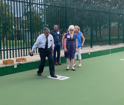 One individual playing bowls as three watch.