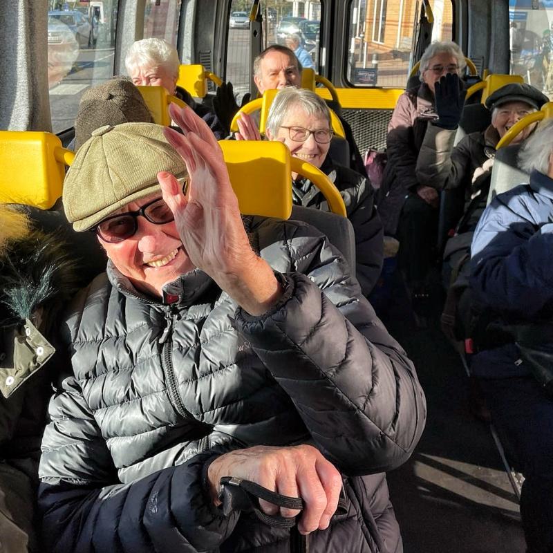 Photograph of passengers smiling and waving on a recent Shopper Bus outing. 