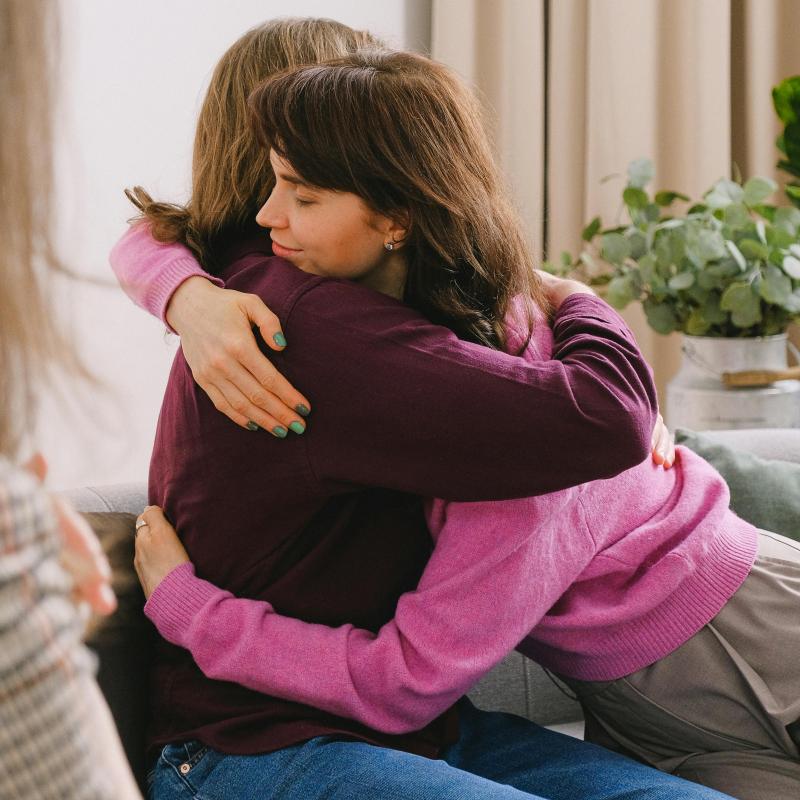 https://www.pexels.com/photo/friends-hugging-while-sitting-with-coach-in-room-7176233/