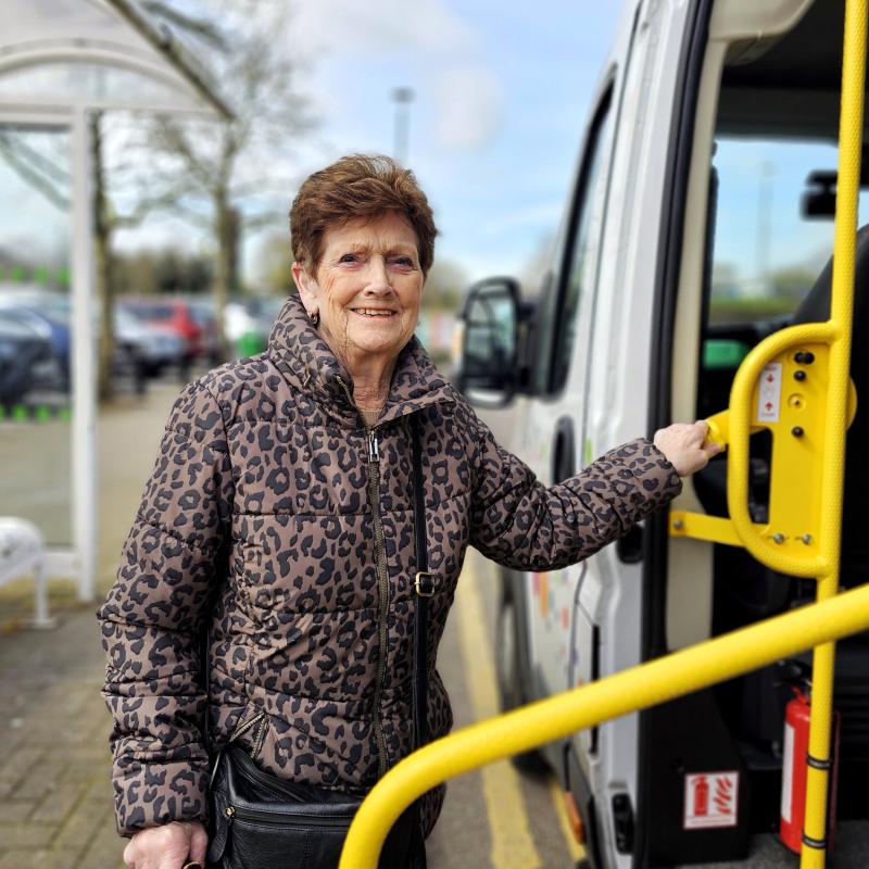 An elderly woman boarding the Shopper Bus.
