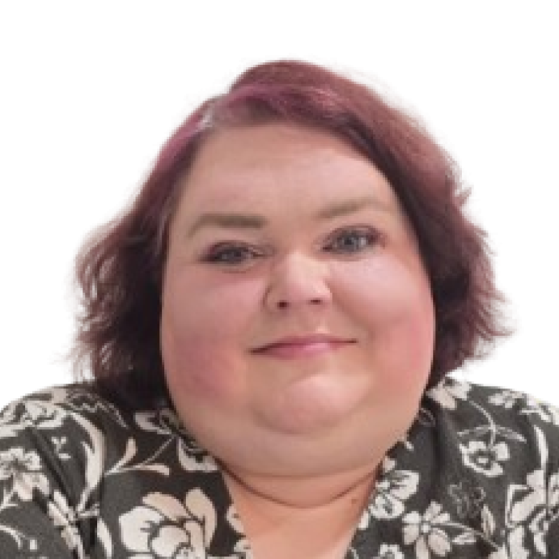 Photograph of a woman with short red hair. She is wearing a black and white patterned top