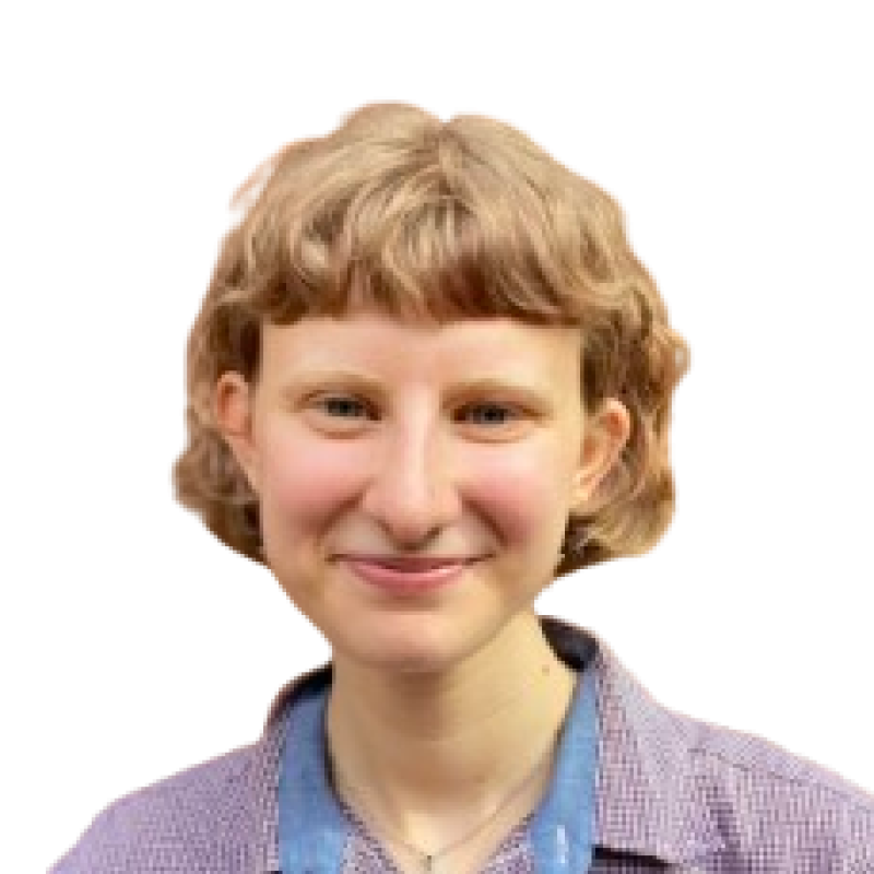 Photograph of a young woman with short, wavy blonde hair. She is wearing a lilac and blue top and smiling at the camera
