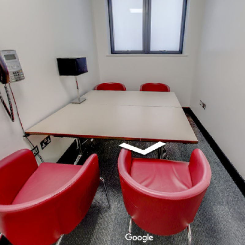Meeting Room 5 at 96 Shenley Road. It has a small square table and four red chairs. There is a phone on the wall.