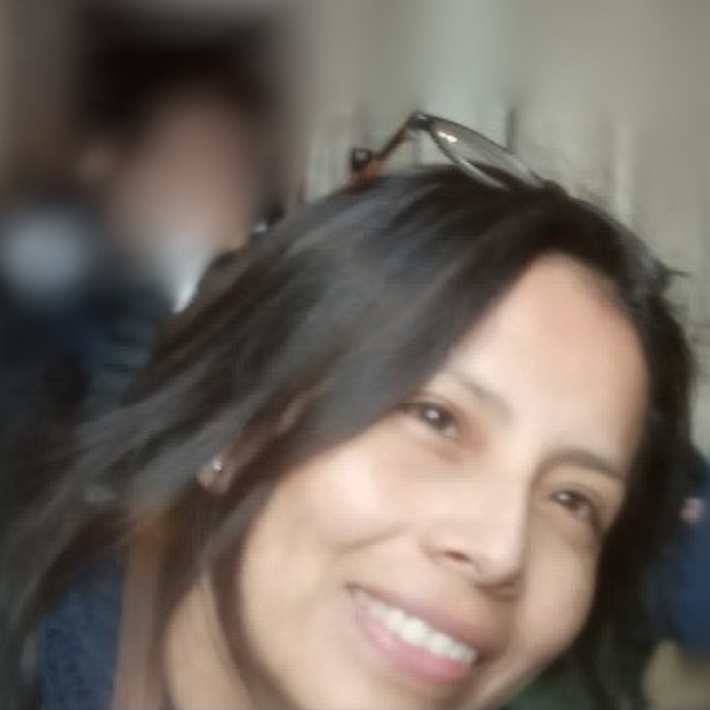 A picture of a lady with dark hair. She is smiling and looking away from the camera