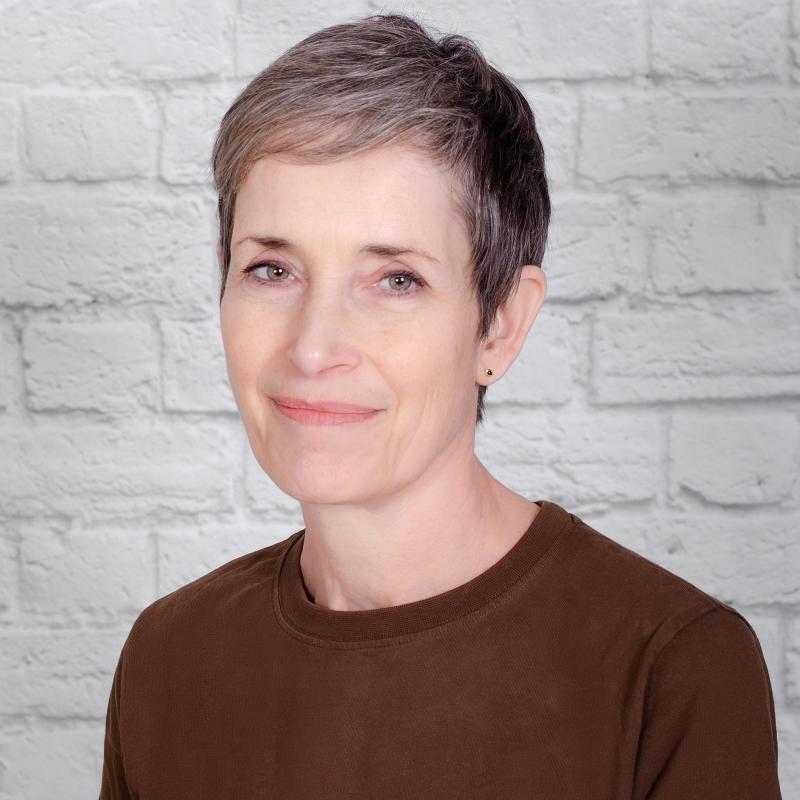 photograph of a smiling woman wearing a brown shirt